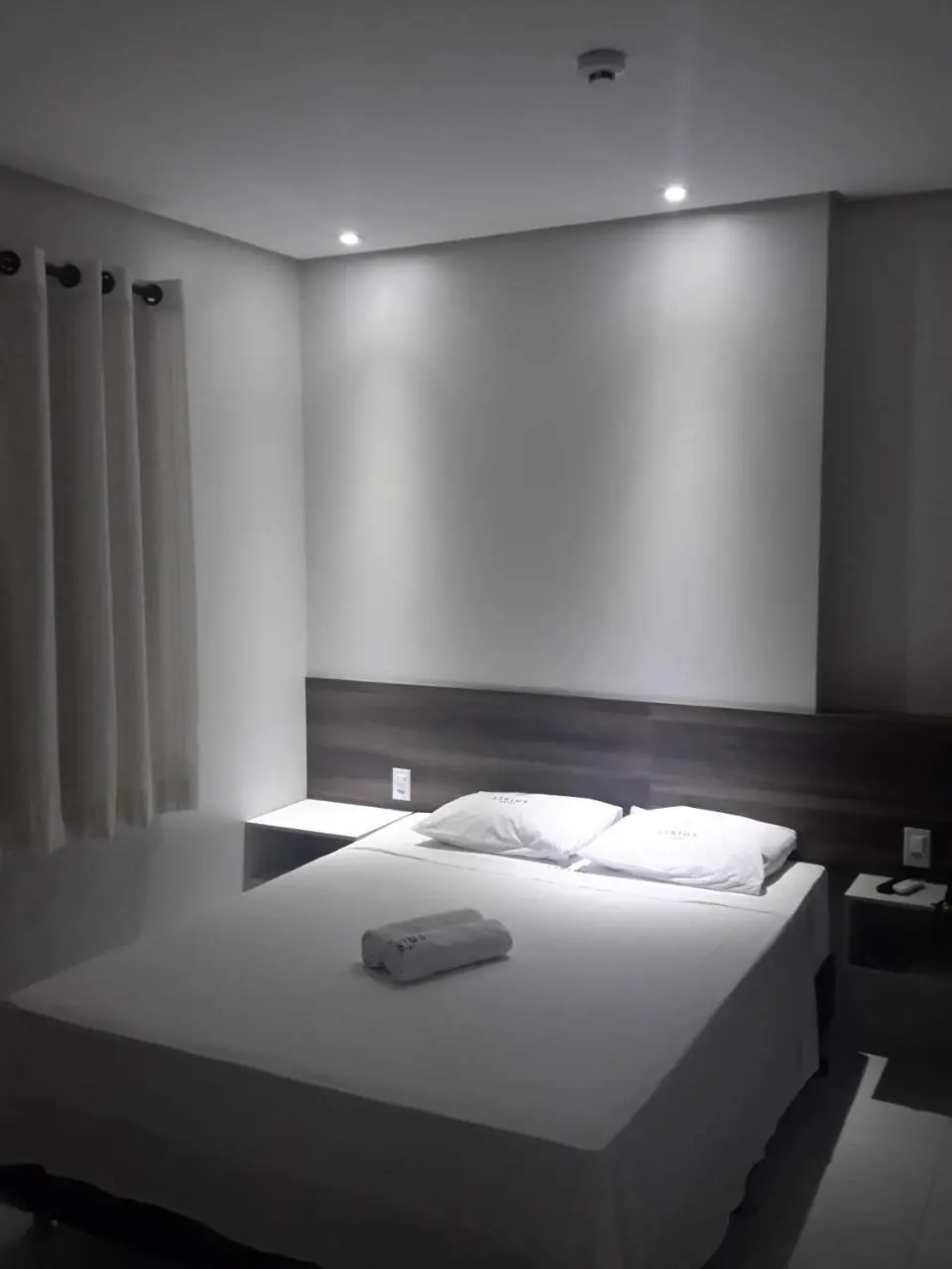 Quarto com cama de casal, mesa lateral e ar-condicionado